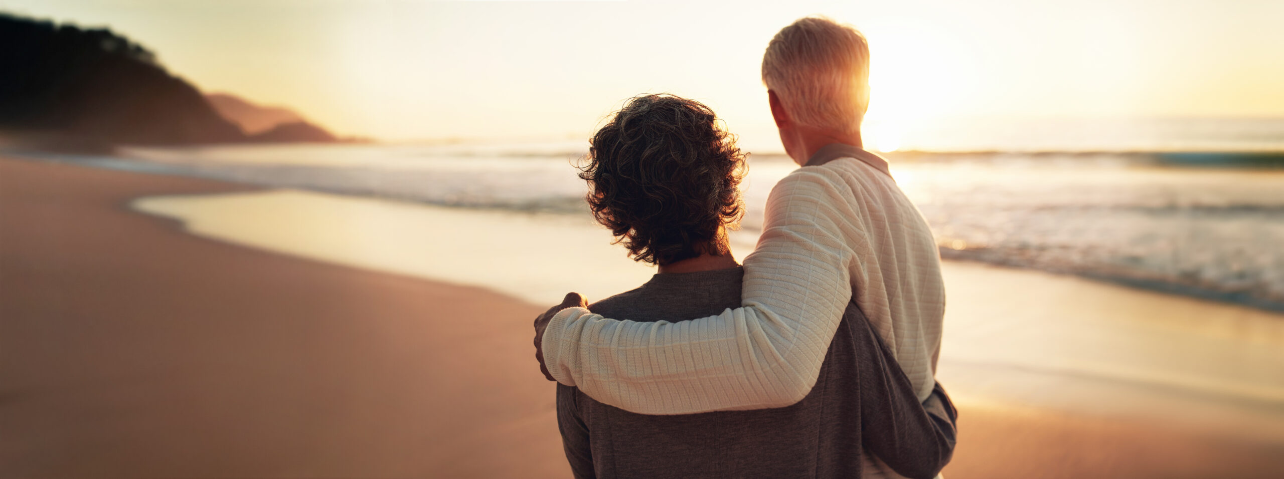 Happy seniors enjoying their golden years of retirement with a beach sunset